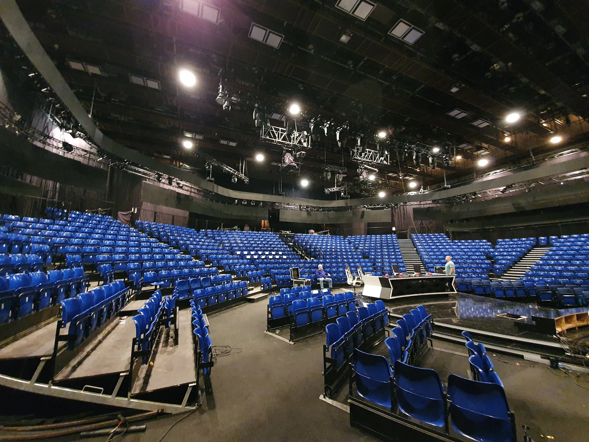 Tribúna Arenaseats s modrými sklápacími sedadlami okolo pódia